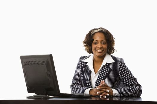 Businesswoman sitting at desk with computer smiling.