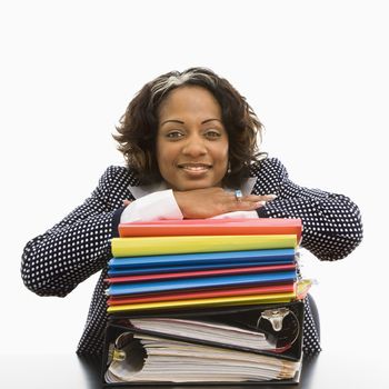 Businesswoman resting head on large stack of work smiling.