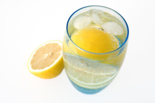 Lemon in glass with mineral water and ice.