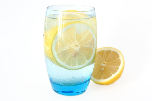 Lemon in glass with mineral water and ice.