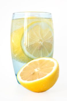 Lemon in glass with mineral water and ice.