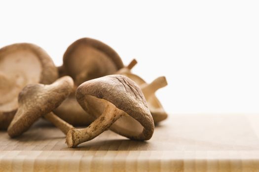 Pile of brown mushrooms on cutting board.