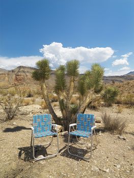 Empty plaid lawn chairs in desert landscape.