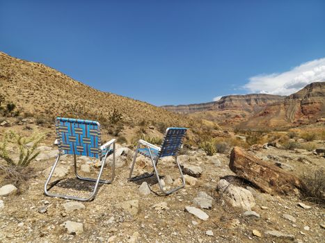 Empty plaid lawn chairs in desert landscape.