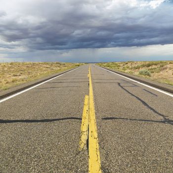 Empty two lane highway leading to desert horizon.