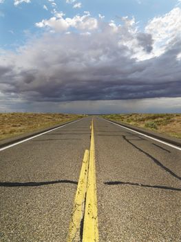 Empty two lane highway leading to desert horizon.