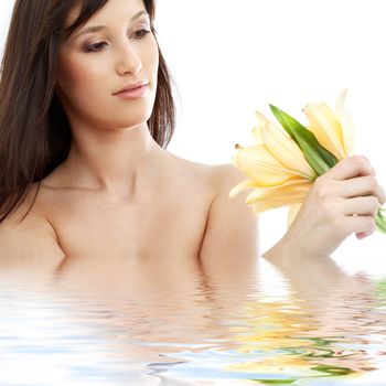 happy brunette with yellow lily flowers in spa