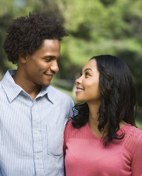 Head and shoulder portrait of smiling couple looking into eachother's eyes.