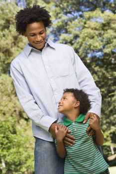 Father with hands on son's shoulders as boy looks up at him.