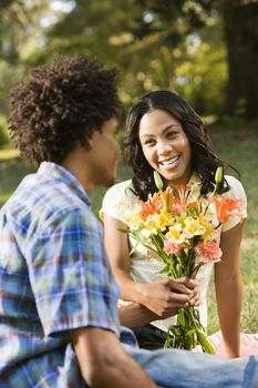 Man giving smiling woman bouquet of flowers.