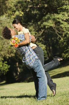 Couple smiling and embracing in park.