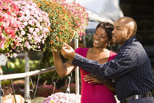 Happy smiling couple picking out flowers at outdoor plant market.