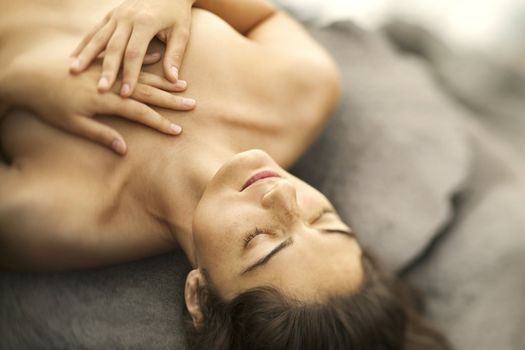 Close up of young nude Caucasian woman lying on rock with eyes closed and hands crossed on chest.