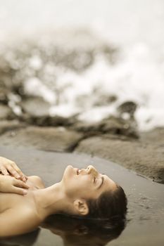 Profile of young nude Caucasian woman lying on beach sunbathing.