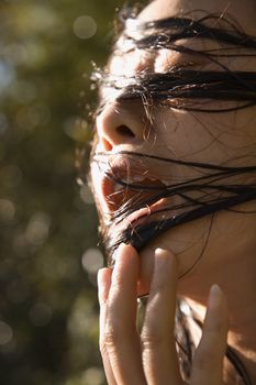 Mid-adult Asian female with wet hair in mouth.