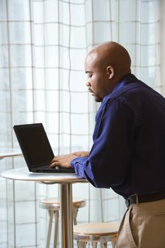 Mid-adult African American male typing on laptop in computer.
