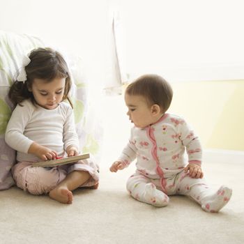 Caucasian girl children sitting on bedroom floor looking at book.