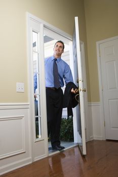 Caucasian businessman at open door with briefcase.