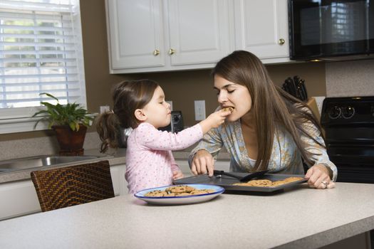 Caucasian girl feeding mother cookies.