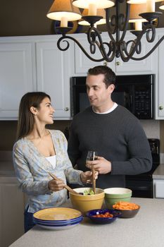 Caucasian couple making salad at kitchen counter.