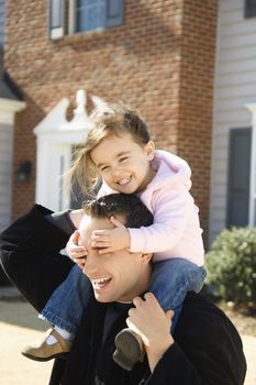 Caucasian father carrying daughter on shoulders.