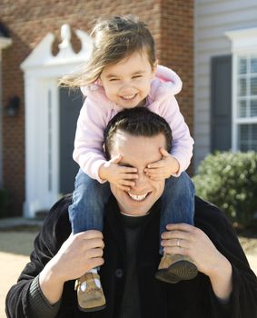 Caucasian father carrying daughter on shoulders.