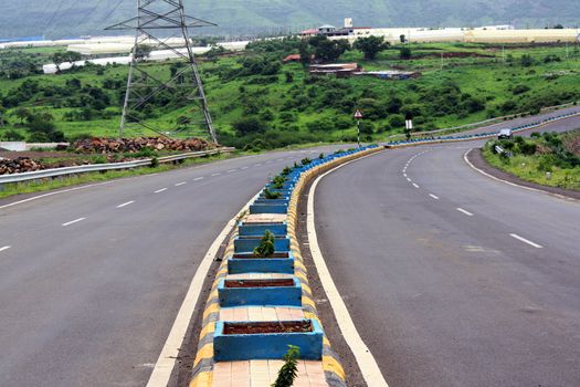 A empty highway turning on a beautiful landscape, in India.