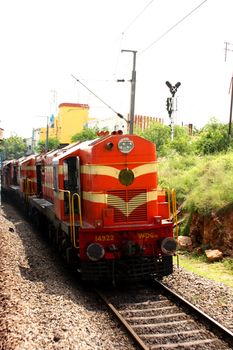 An orange locomotive / engine of a moving train in India.