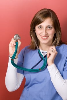 This nurse is holding up her stethoscope and smiling.