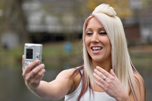 A young woman taking pictures of herself with a digital camera.