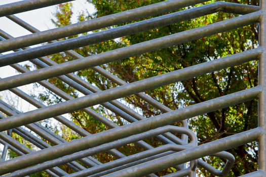 Intersections of steel railing on stairwell with green trees in background