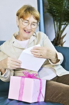 Elderly woman opening birthday card and present