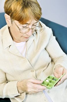 Elderly woman holding pill box with medication