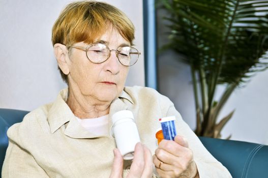 Elderly woman reading warning labels on pill bottles with medication