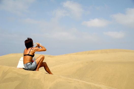 Woman is drinking water in the desert