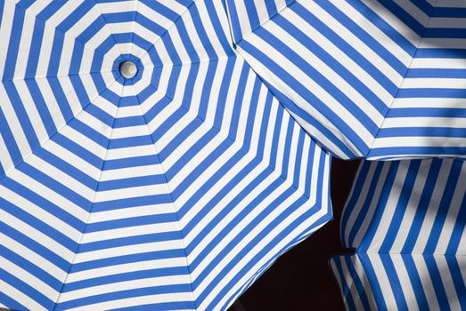 overlapping sun shade umbrellas with white and blue stripes