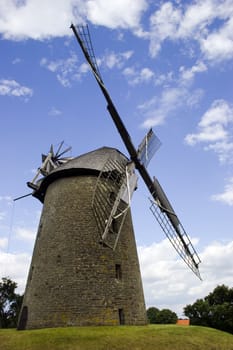 Old wind mill against blue sky with white clouds