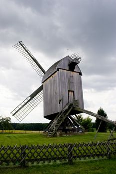 Old wooden wind mill against sky with white clouds