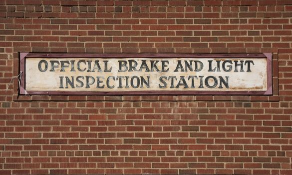 vintage brake and light inspection sign against red brick wall from an old garage