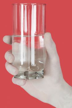 Glass of water on hand on the red background