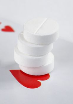 Roll of tablets and heart on the playing card background
