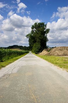 Narrow rural road and blue sky with white clouds