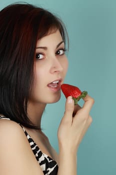 beautiful young woman eating a fresh strawberry