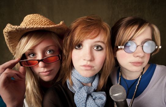Portrait of three pretty young girls with a microphone on green background
