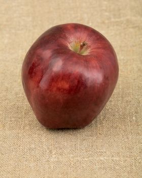 Red apple on the brown sacking background