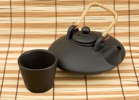 Black ceramic chinese teapot and mugs on the mat