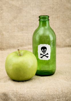 Green bottle with sticker skull and crossbones and apple