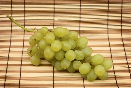 Green grapes on the wooden mat background