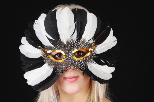 cute young blond girl with feather mask, black background