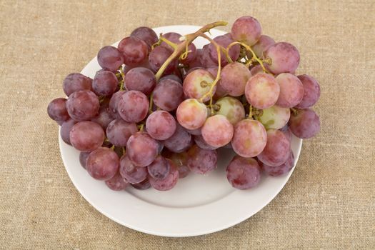 Red rip grapes on plate on the sacking background